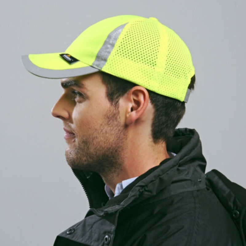 Homme portant une casquette jaune sur fond gris.
