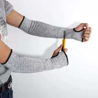 On voit une paire de bras qui portent des manchettes anticoupures argentées avec une encoche pour le pouce. La personne manipule un cutter.