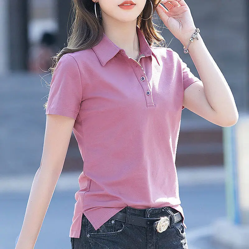 Femme portant un polo rose et se trouvant dans une rue.
