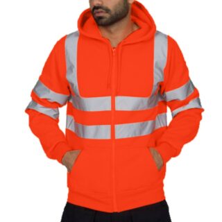 On voit un homme brun et barbu avec les mains dans les poches. Il porte un sweat haute visibilité orange avec des bandes réfléchissantes.