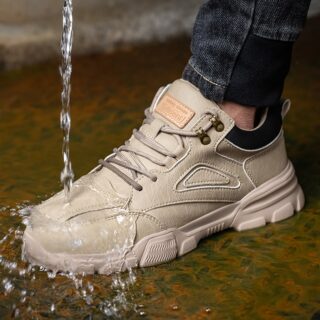 Chaussure de sécurité beige sur un sol marron avec de l'eau qui coule dessus.